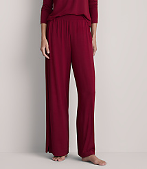 A person stands in loose-fitting burgundy pajamas against a plain, light gray background. carousel Product Image 2