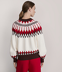 A woman in a cream, red, and brown patterned sweater stands against a plain, light gray background. carousel Product Image 3