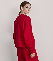 A woman in a red sweater and pants stands against a plain, light-colored background. carousel Product Image 3