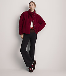 A woman in a maroon puffer jacket and black flared pants stands against a plain gray background. carousel Product Image 2