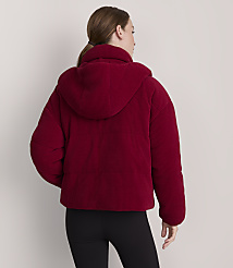 A woman in a red corduroy puffer jacket stands against a plain white background. carousel Product Image 3