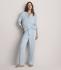 A woman in light blue pajamas stands against a plain, light gray background. carousel Product Image 1