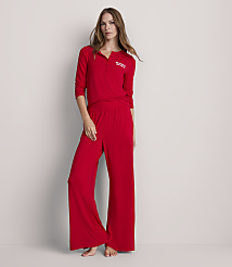 A woman in red pajamas stands against a plain, light gray background. carousel Product Image 1