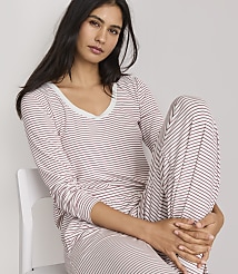 A woman in striped pajamas sits on a white chair against a plain background. carousel Product Image 2