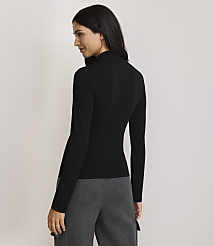 A woman in a black turtleneck and gray pants stands against a plain, light-colored background. carousel Product Image 3