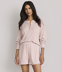 A woman in a pink pajama set stands against a plain gray background. carousel Product Image 1