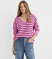 A young woman in a pink and purple striped sweater and blue jeans stands against a plain white background. carousel Product Image 2