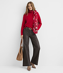 A woman in a red turtleneck and dark flared pants stands against a plain white background, holding a brown tote bag and wearing a patterned scarf and animal-print boots. carousel Product Image 2