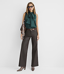 A woman in a teal bow-neck blouse and dark wide-leg pants stands against a plain white background. carousel Product Image 2