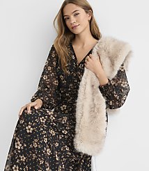 A woman in a floral dress holds a fluffy faux fur stole in front of a plain white background. carousel Product Image 2
