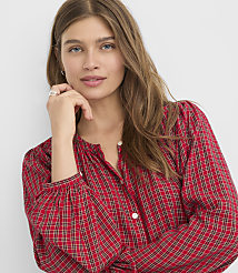 A woman with long brown hair and a red plaid shirt rests her chin on her hand against a plain white background. carousel Product Image 2