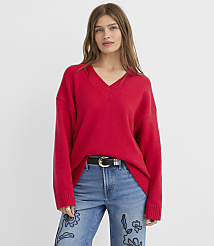 A woman in a red v-neck sweater and embroidered jeans stands against a plain white background. carousel Product Image 2