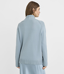A woman in a light blue turtleneck sweater and skirt stands against a plain white background. carousel Product Image 3
