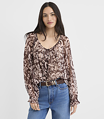 A woman in a floral print blouse and jeans stands against a plain white background. carousel Product Image 1