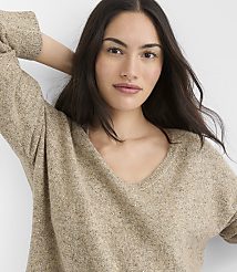 A woman with long dark hair and a v-neck sweater is in the foreground, with a plain white background. carousel Product Image 1