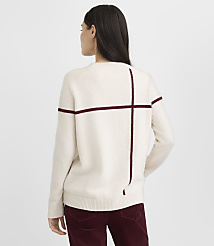 A woman in a cream-colored sweater with maroon stripes stands against a plain white background. carousel Product Image 3