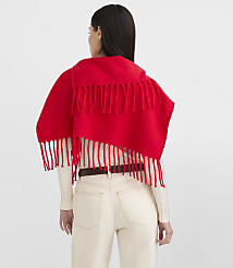A woman in a white ribbed shirt and cream pants wears a bright red fringed scarf over her shoulders against a plain white background. carousel Product Image 3