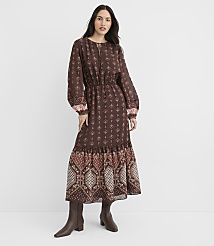 A woman in a long, patterned brown dress and boots stands against a plain white background. carousel Product Image 2