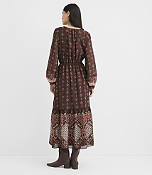 A woman in a long, patterned brown dress and boots stands against a plain white background. carousel Product Image 3