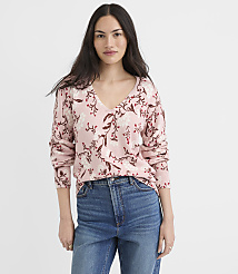 A woman in a floral pink sweater and blue jeans stands against a plain white background. carousel Product Image 1