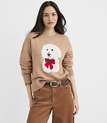 A woman in a tan sweater with a white dog graphic and brown corduroy pants stands against a plain white background. carousel Product Image 1