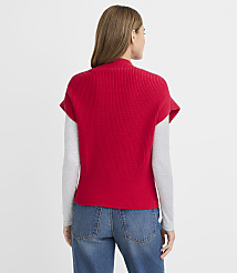 A woman in a red sweater vest and blue jeans stands against a plain white background. carousel Product Image 3