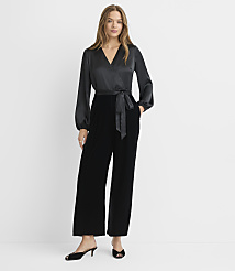 A woman in a black satin wrap top and velvet pants stands against a plain white background. carousel Product Image 1