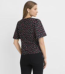 A woman in a floral print top and black pants stands against a plain white background. carousel Product Image 3