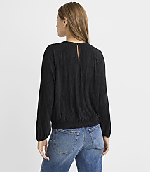 A woman in a black textured blouse and blue jeans stands against a plain gray background. carousel Product Image 3