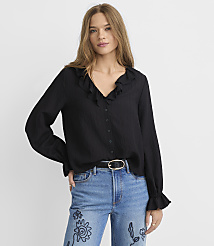 A woman in a black ruffled blouse and blue jeans stands against a plain white background. carousel Product Image 1