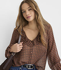A young woman with long, wavy brown hair wears a brown plaid blouse with a ruffled neckline and a dark crossbody bag, set against a plain white background. carousel Product Image 2