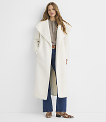 A woman in a long white coat and jeans stands against a plain white background. carousel Product Image 1