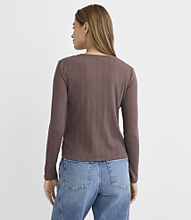 A woman in a brown ribbed long-sleeved shirt and blue jeans stands against a plain, light gray background. carousel Product Image 3