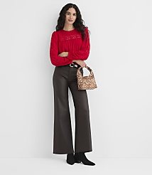 A woman in a red top and brown pants stands with a patterned bag against a plain white background. carousel Product Image 2