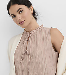 A woman in a pink ruffled top and cream cardigan is shown against a plain white background. carousel Product Image 1