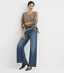 A woman in a brown v-neck sweater and wide-leg jeans stands against a plain white background. carousel Product Image 2