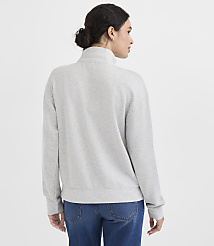 A woman in a grey quarter-zip sweatshirt and blue jeans stands against a plain white background. carousel Product Image 4