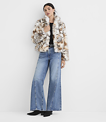 A woman in a fluffy patterned jacket and wide-leg jeans stands against a plain white wall. carousel Product Image 3