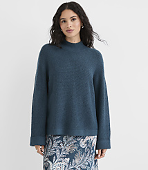 A woman in a teal sweater and patterned skirt stands against a plain white background. carousel Product Image 2
