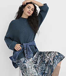 A woman in a teal sweater and patterned skirt poses against a plain white background. carousel Product Image 1