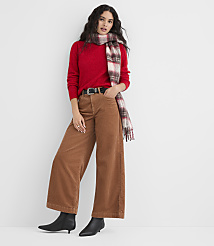 A woman in a red sweater, brown corduroy pants, and a plaid scarf stands against a plain white background. carousel Product Image 2