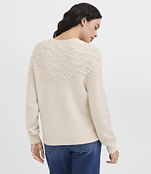 A woman in a cream-colored sweater and blue jeans stands against a plain white background. carousel Product Image 3