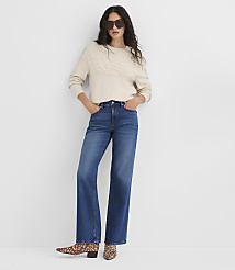 A woman in a cream cable-knit sweater and wide-leg jeans stands against a plain white background. carousel Product Image 2