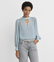 A woman in a light blue blouse and grey jeans stands against a plain, light grey background. carousel Product Image 1