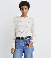 A woman in a cream-colored, patterned sweater and blue jeans stands against a plain white background. carousel Product Image 2