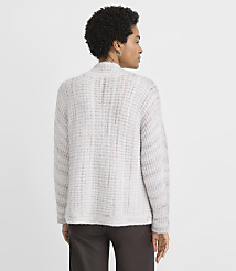A woman in a textured, light-colored cardigan stands against a plain, light gray background. carousel Product Image 4