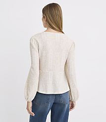 A woman in a textured cream blouse and blue jeans stands against a plain, light gray background. carousel Product Image 3