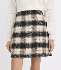 A person wears a fuzzy, plaid mini-skirt in the foreground, with a cream-colored, textured sweater in the background. carousel Product Image 2