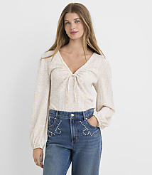 A woman in a patterned blouse and embellished jeans stands against a plain white background. carousel Product Image 2