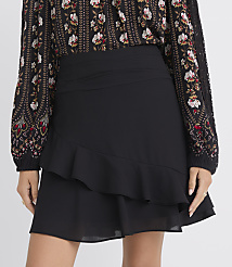 A black ruffled mini skirt with a floral print blouse is shown against a plain background. carousel Product Image 2
